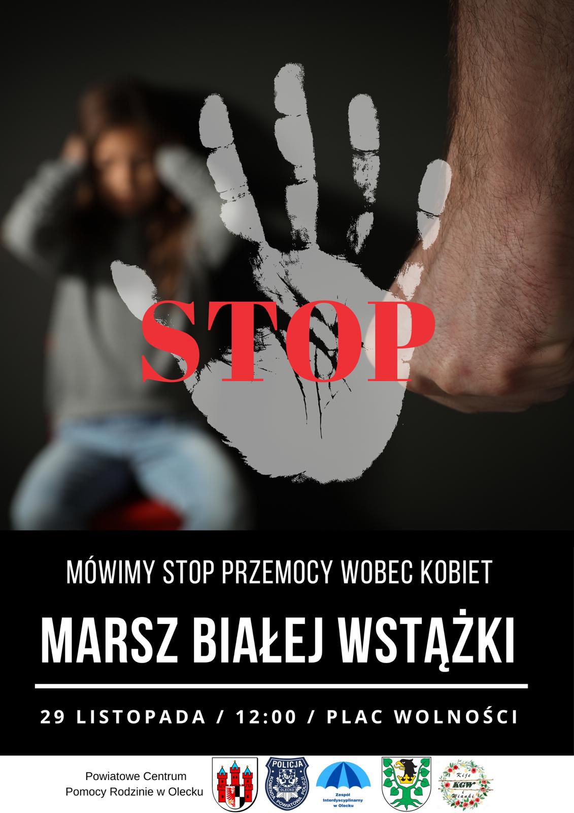 Dłoń, a na niej napis stop. W tle dziewczynka siedzi i zasłania dłońmi uszy. Obok zaciśnięta dłoń mężczyzny. Pod nim biały napis na czarnym tle. Mówimy stop przemocy wobec kobiet. Marsz Białej Wstążki. 29 listopada, 12:00, Plac Wolności. Pod nimi napis: Powiatowe Centrum Pomocy Rodzinie w Olecku i 4 logotypy urzędów, policji, organizacji i zespołu.